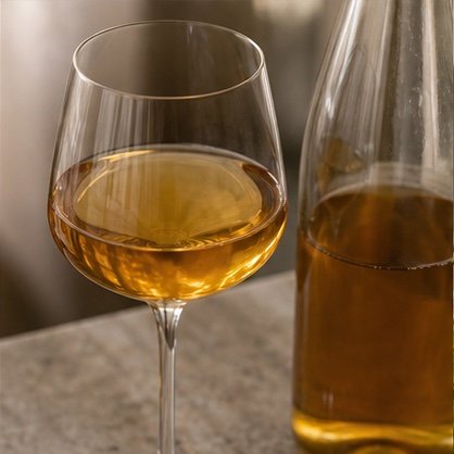 Amber skin-contact wine in a glass beside its bottle